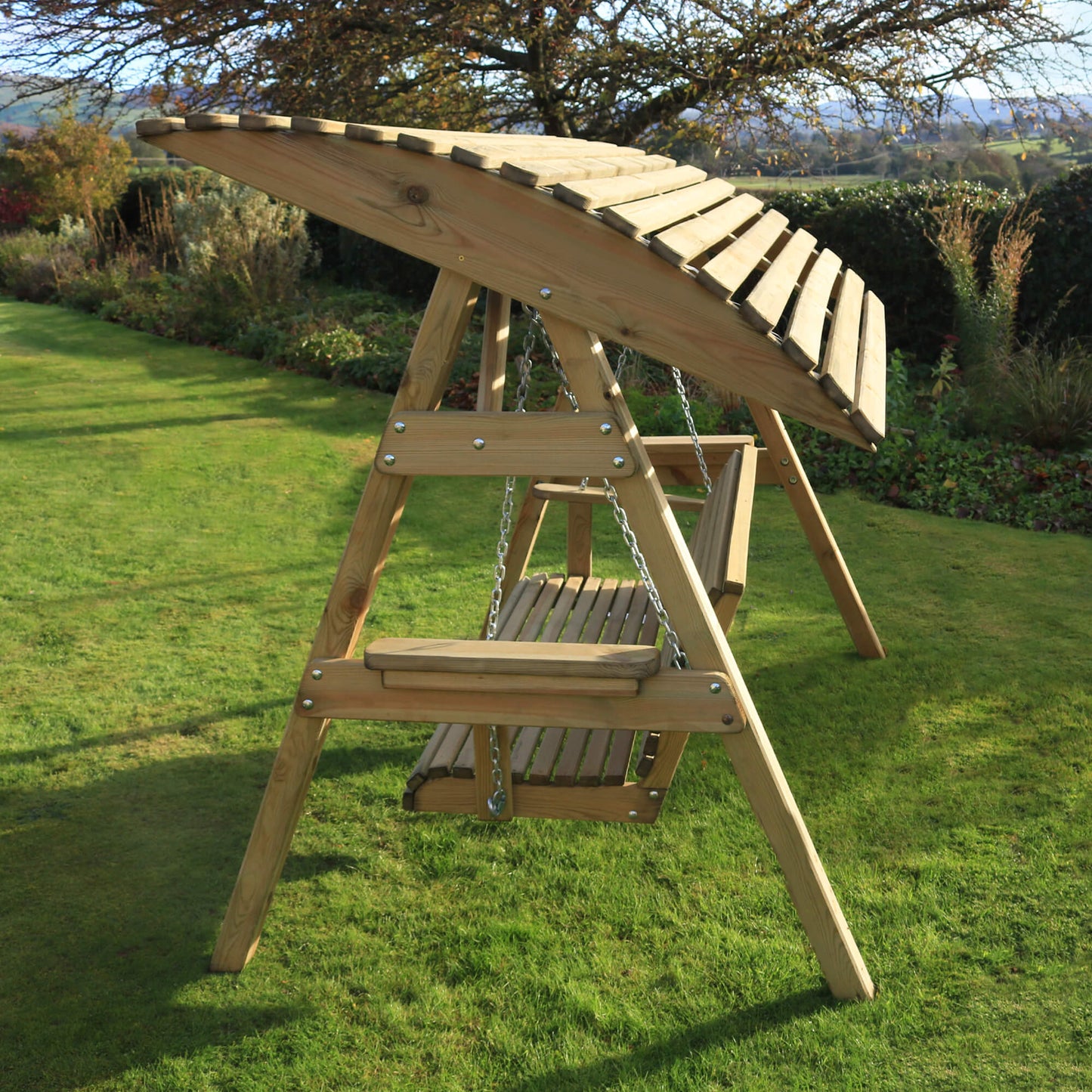 Wooden swing set on a grassy area with trees in the background